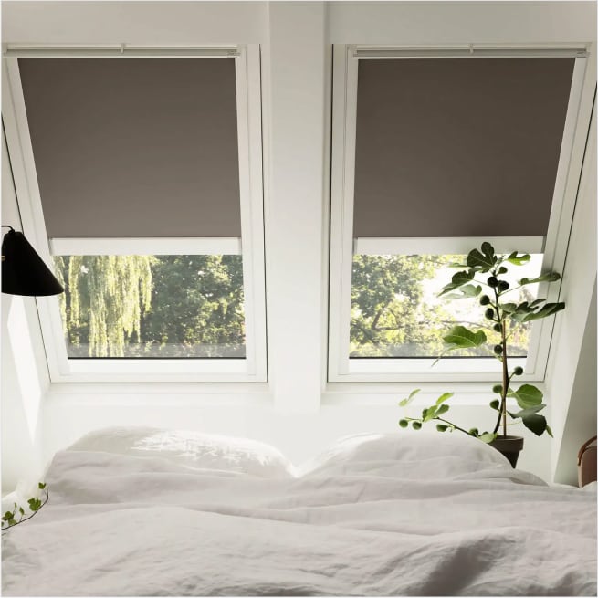 Foto di due finestre Velux con tende a rullo.