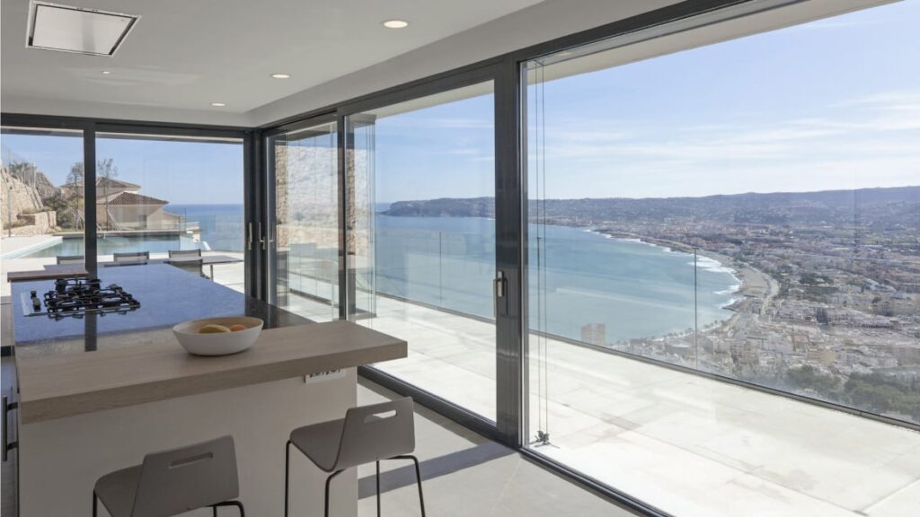 Vista interna di una cucina con vista sul mare, resa possibile da finestre Optimedia a tutta parete
